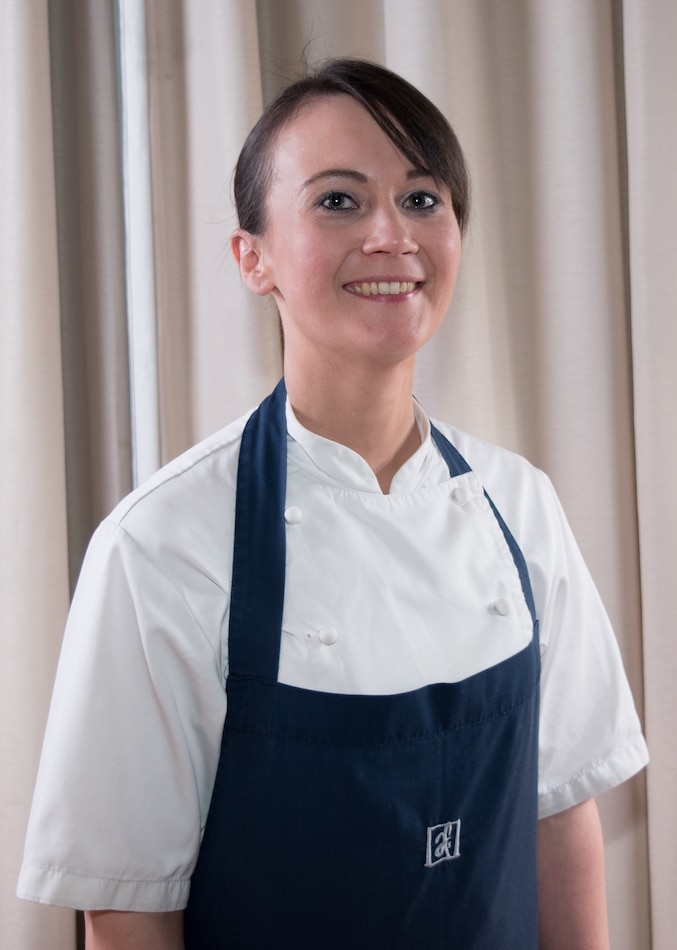 Une Femme Portant Une Toque De Chef Se Tient Dans Un Restaurant.